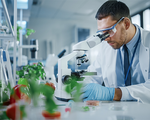 Homem utilizando microscópio.