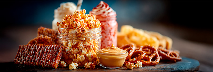 A variety of movie theater treats, including buttered popcorn, chocolates, candy, and cookies, perfect for watching movies at home or at the theater.