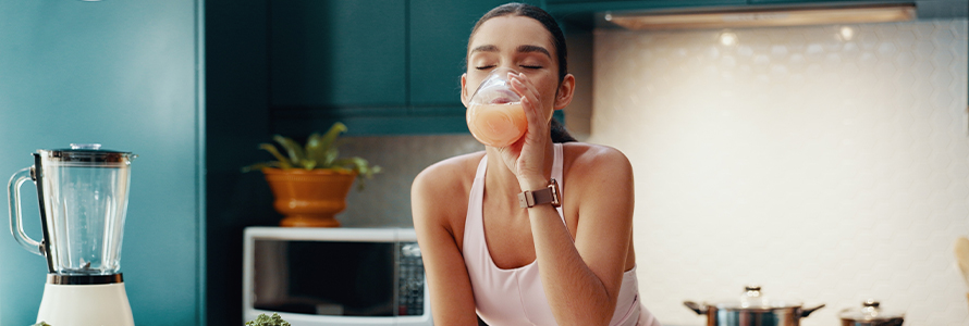 Mulher tomando smoothie na cozinha