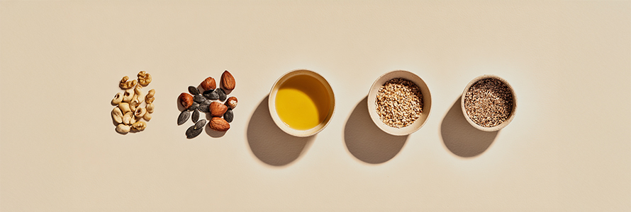 Nuts, seeds, and golden oil on beige background.