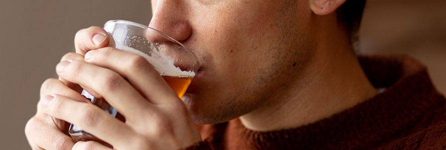 Primer plano de hombre bebiendo cerveza artesanal espumosa en vaso