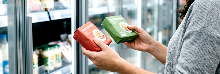 Woman comparing frozen food packages at the supermarket